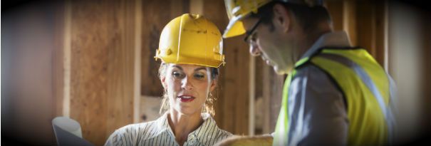 A female construction manager shares a blueprint with a worker.