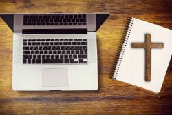 a cross on a notebook next to a laptop